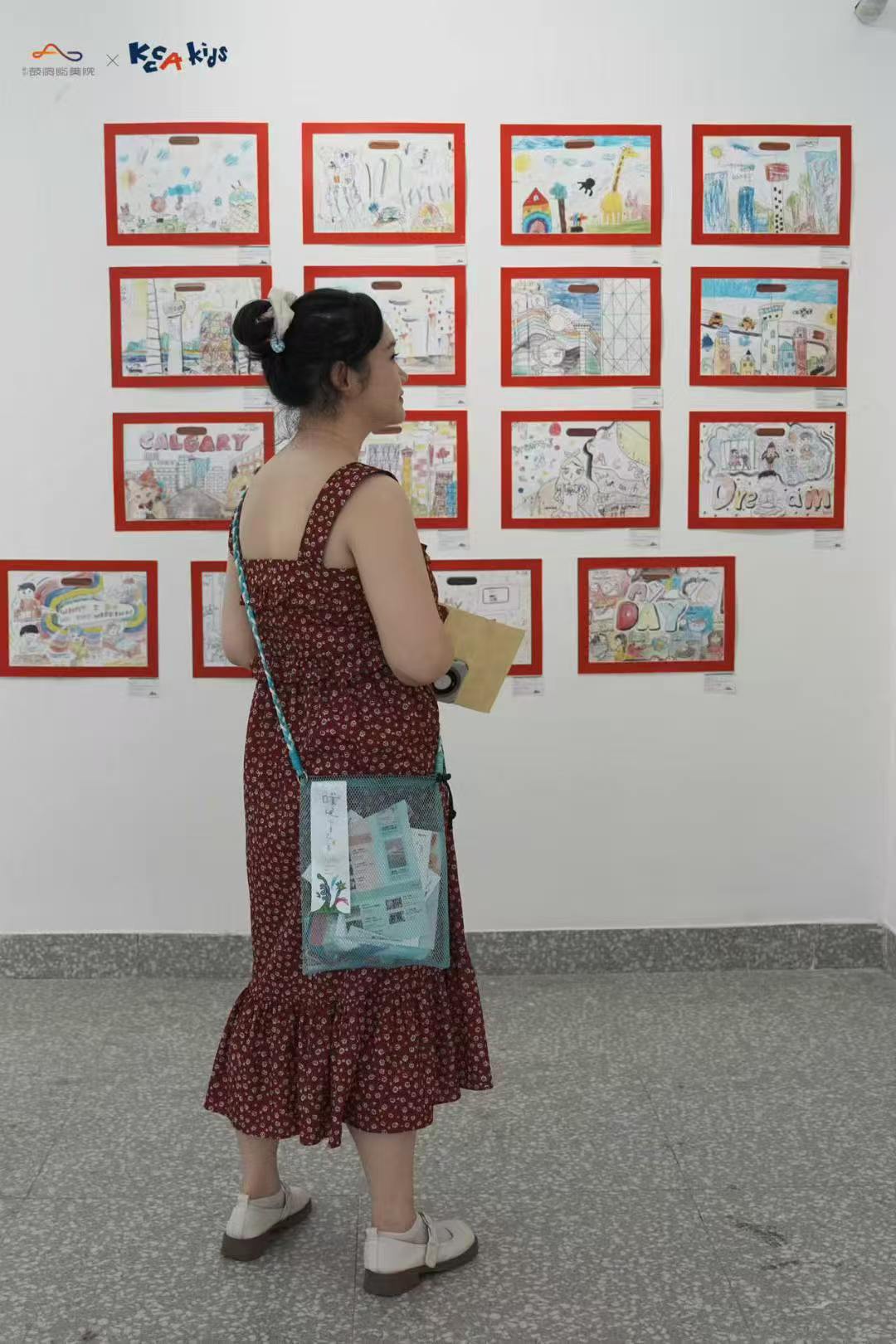Visitor looking at framed children's artworks