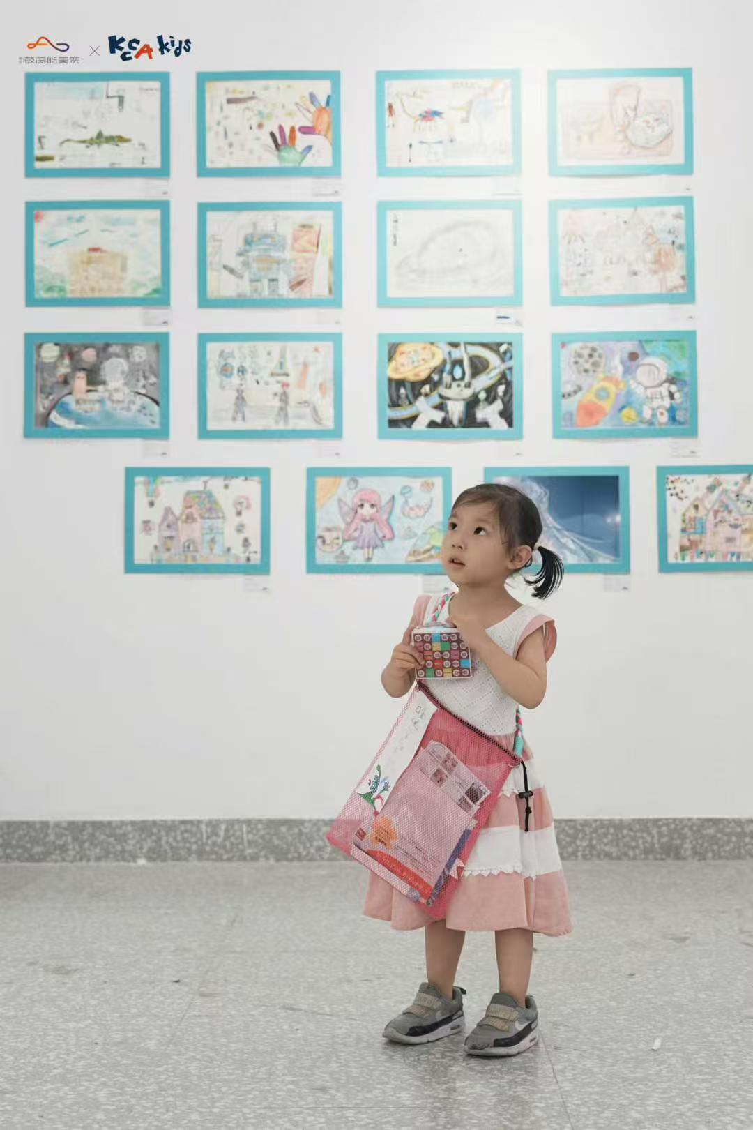 Young visitor standing in front of children's drawings