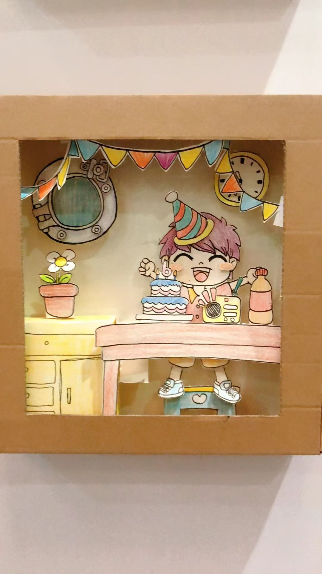 Birthday themed student artwork in a cardboard display box