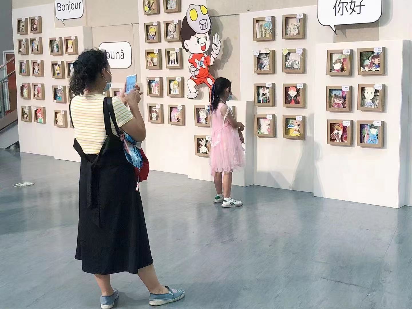 Visitor photographing student artworks at the exhibition wall