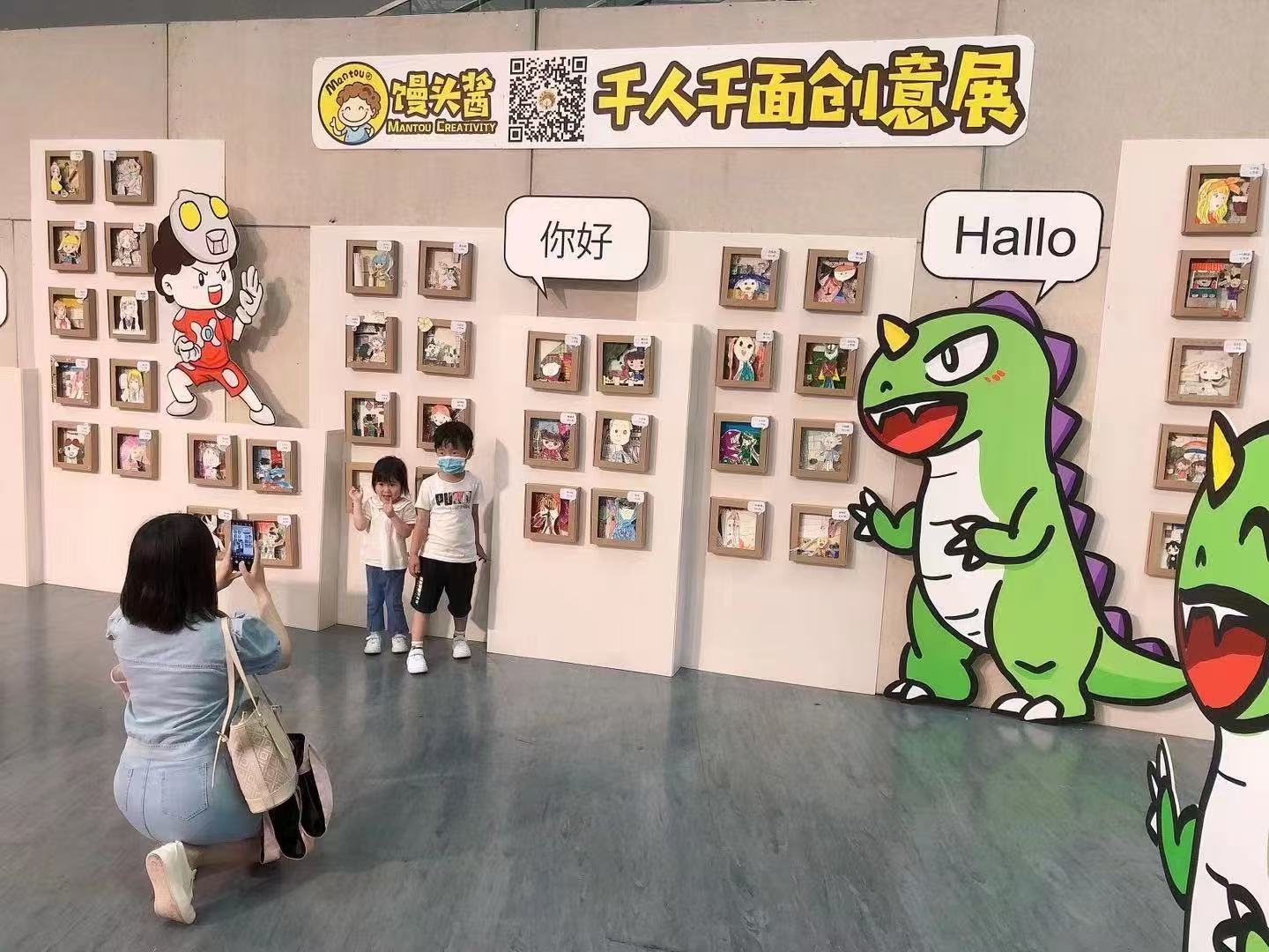 Children posing in front of the A Thousand Faces Creative Exhibition wall