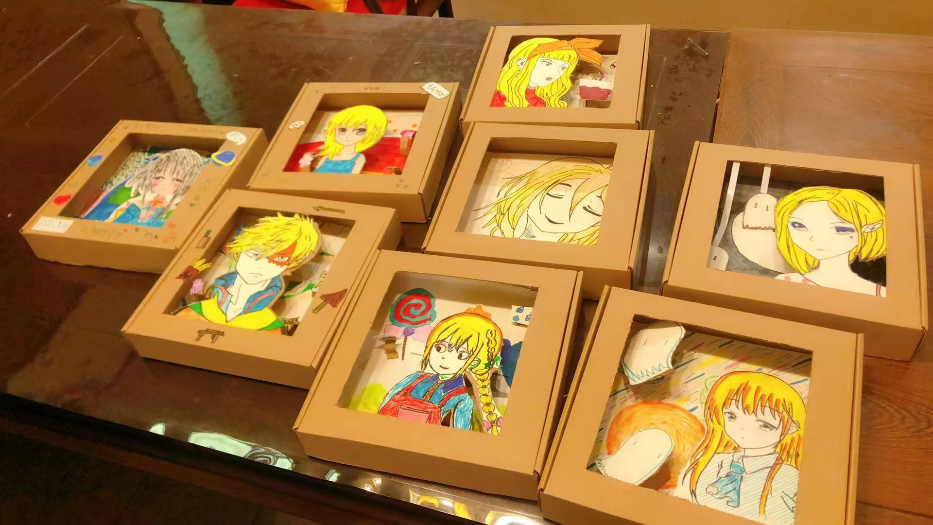 Several student cardboard frame artworks arranged on a table