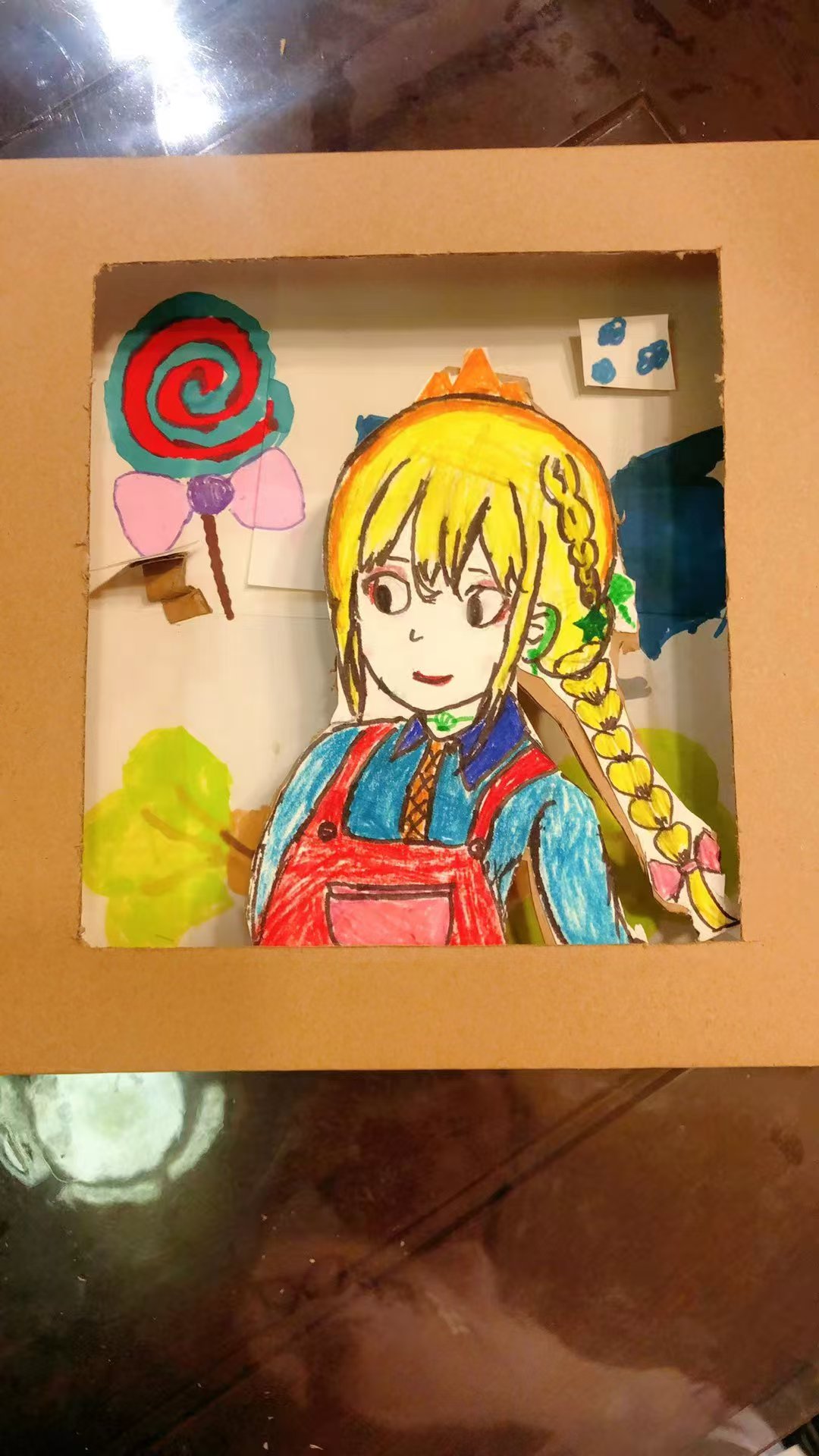 Student artwork of a braided character with candy in a cardboard frame