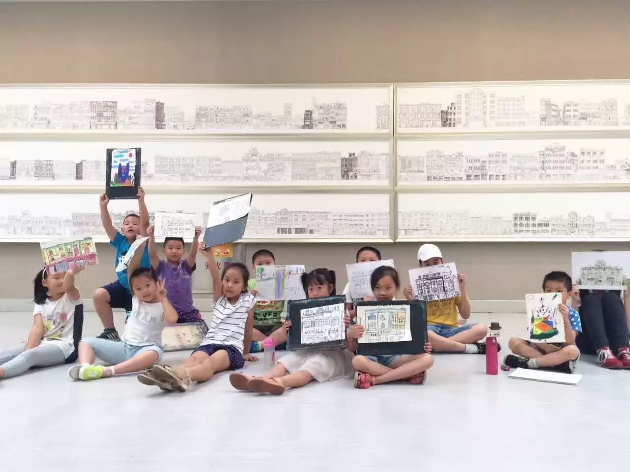 Art training students holding drawings in front of a studio wall