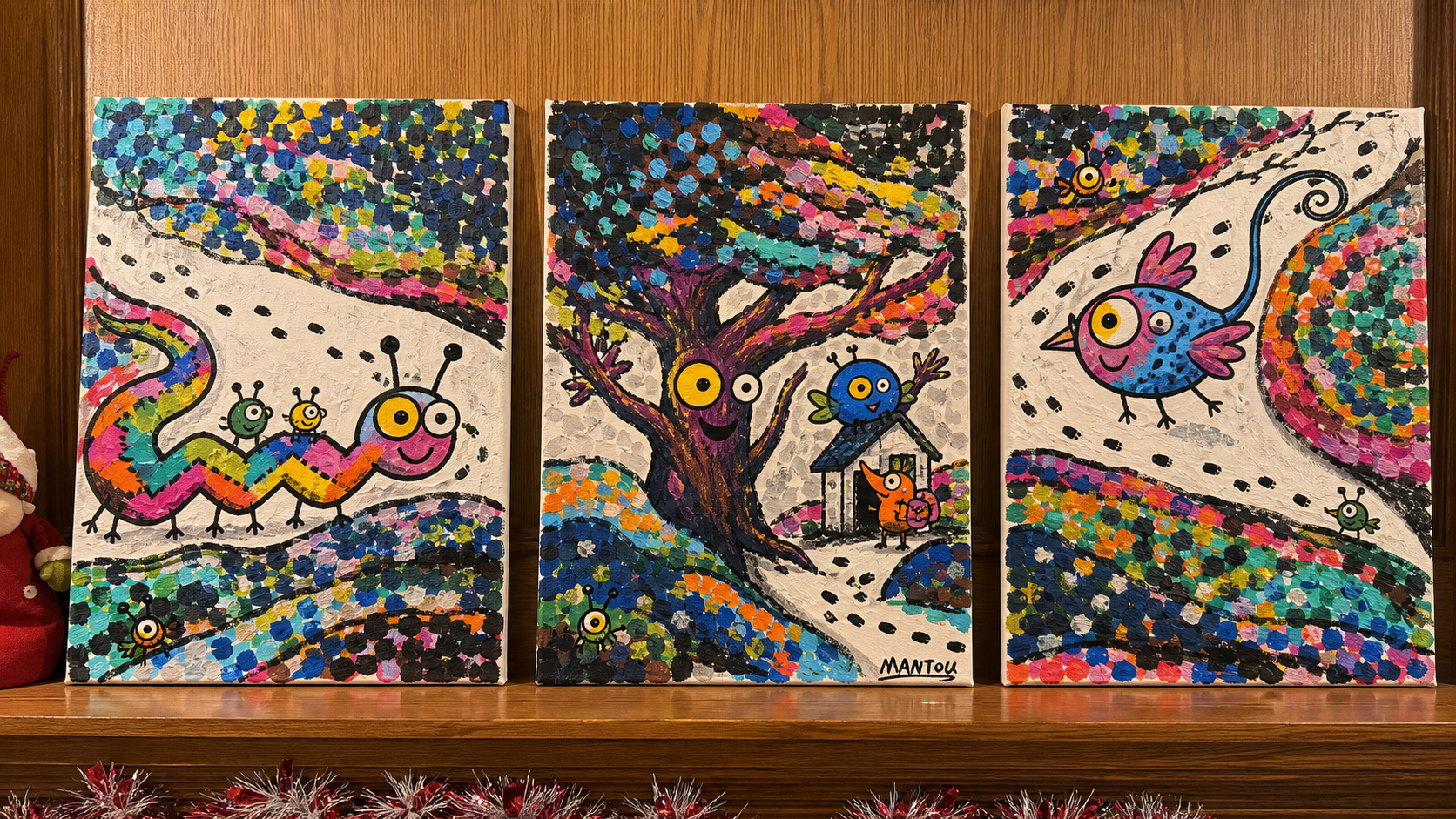 Three acrylic canvas paintings displayed together on a wooden shelf